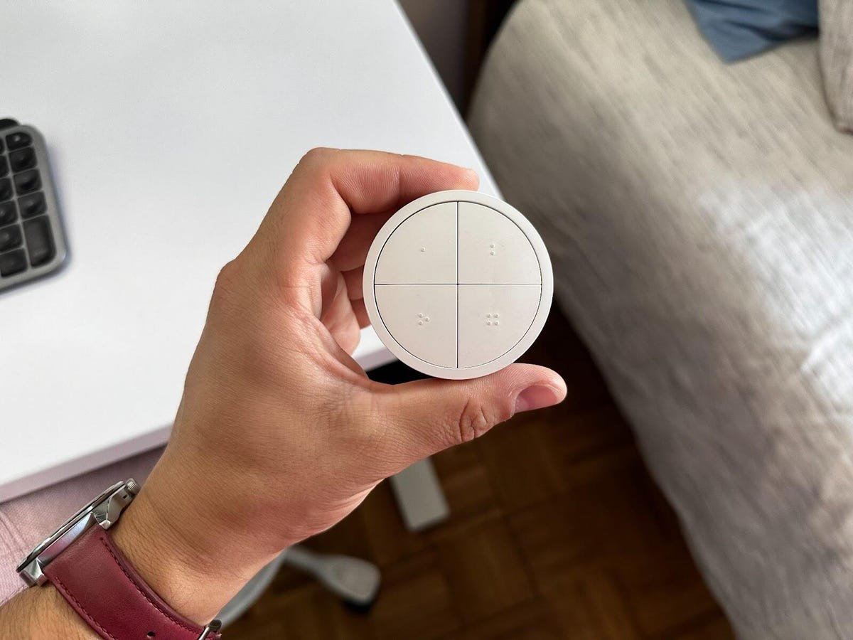 hand holding philips hue tap switch above a desk surface