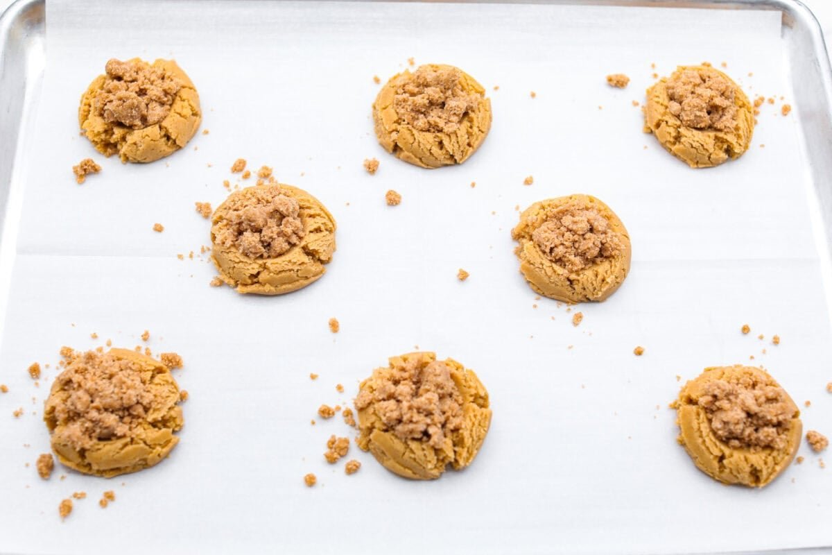 Overhead shot of the coffee cake cookie dough with streusel sprinkled over the top, on parchment paper ready to go in the oven.