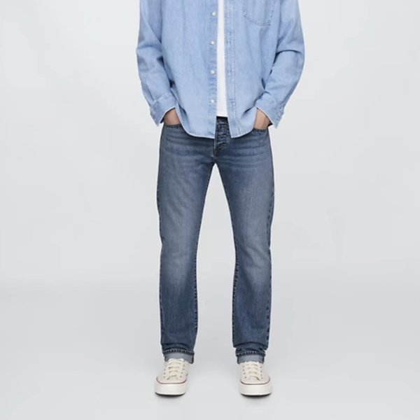 a man wearing slim fit denim jeans with a button front shirt and casual shoes